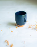 Blue ceramic mug on a light surface with dried flowers